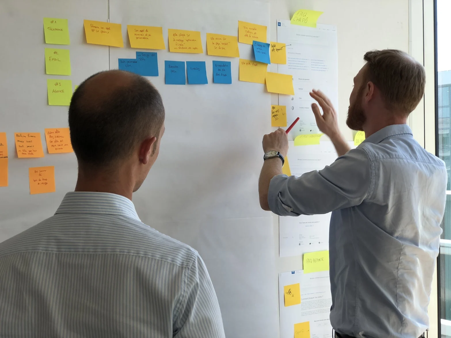 Team members arranging sticky notes on a process board