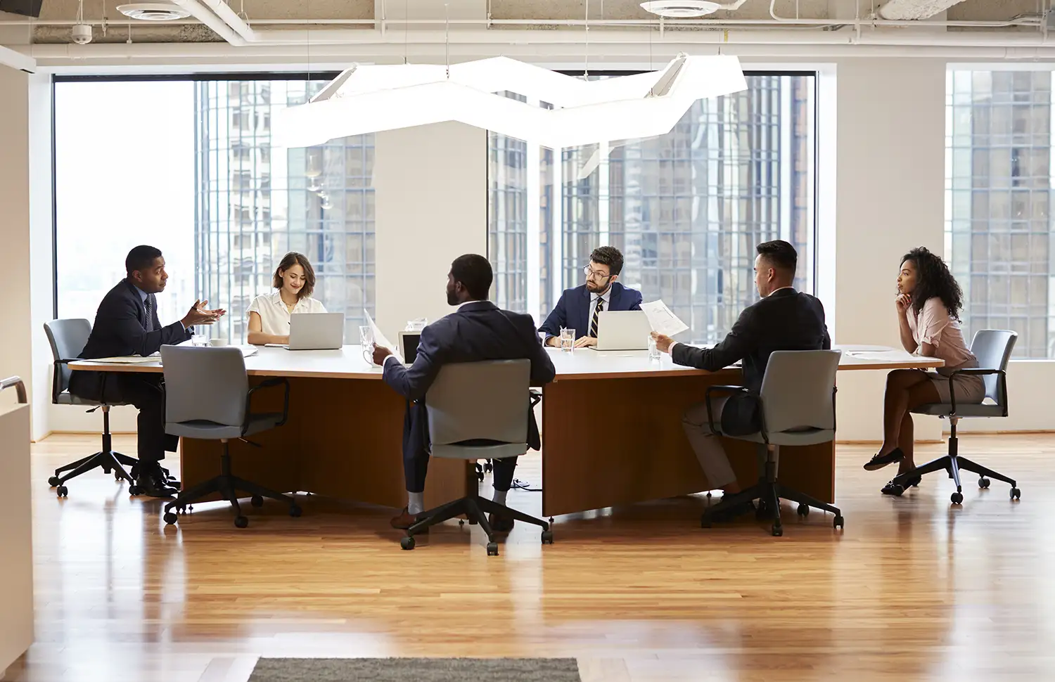 A group of enterprise level individuals sitting around a conference table talking about digital transformation and lean strategy.